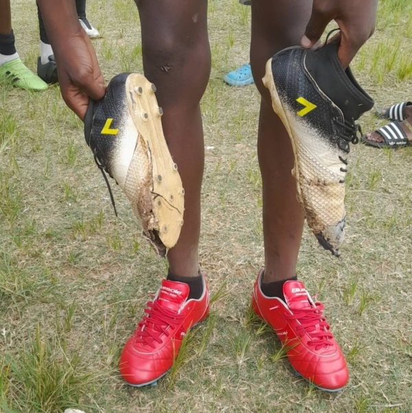 [ soccer shoes ] [ Zambia ] He is wearing new shoes and holding old shoes.