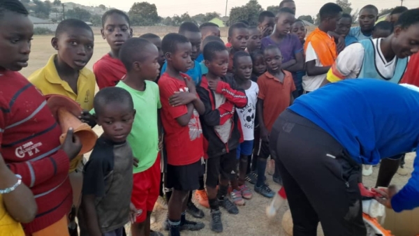 コーチがチームメンバーにサッカー用品を配る準備をしています。みんな興味津々です