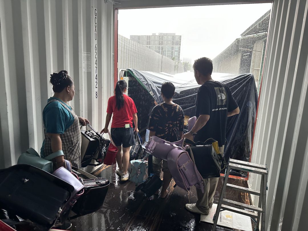 雨で蒸し暑い中、みんなでランドセルを運びます