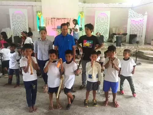 寄付されたリコーダーやハーモニカを吹く子供達。着ているのは日本の体操服です。